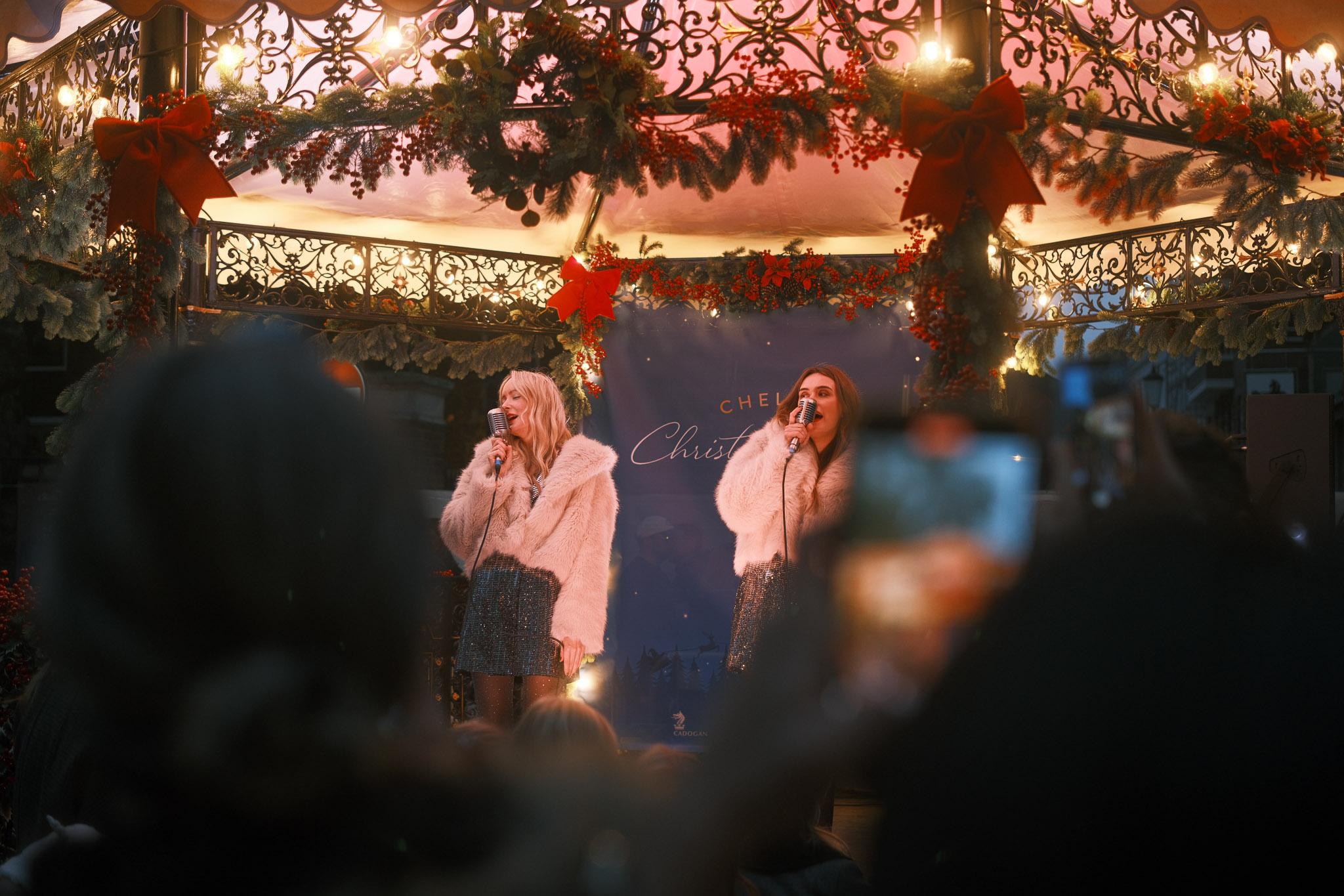 two ladies on a festively decorated stage, singing